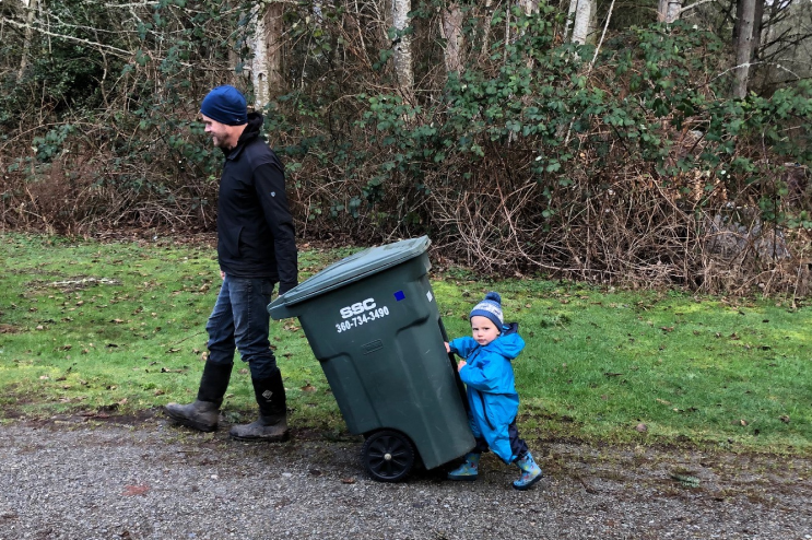 A man and a kid with garbage bin