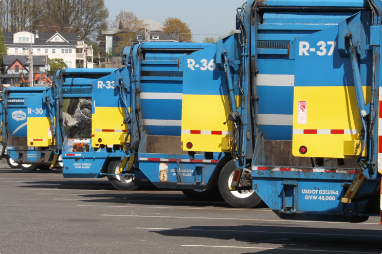 Garbage pickup trucks parked in a line