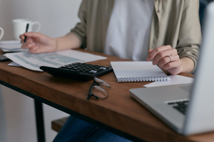 Woman sitting at a desk with a calculator and a laptop